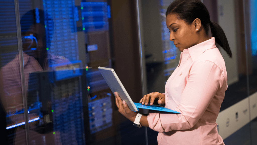 a person holding a laptop in front of a server room