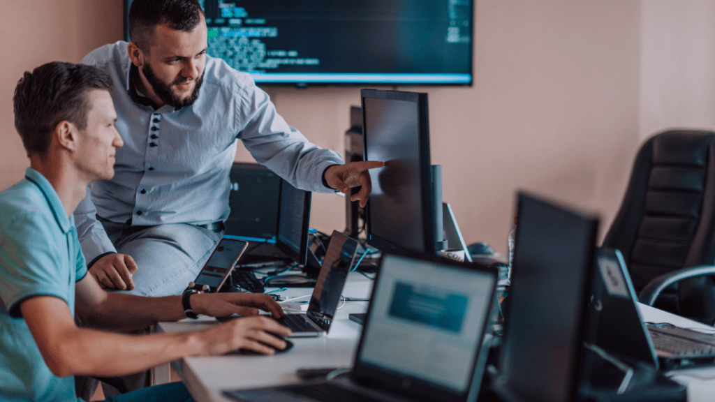 two individuals working on computers in an office