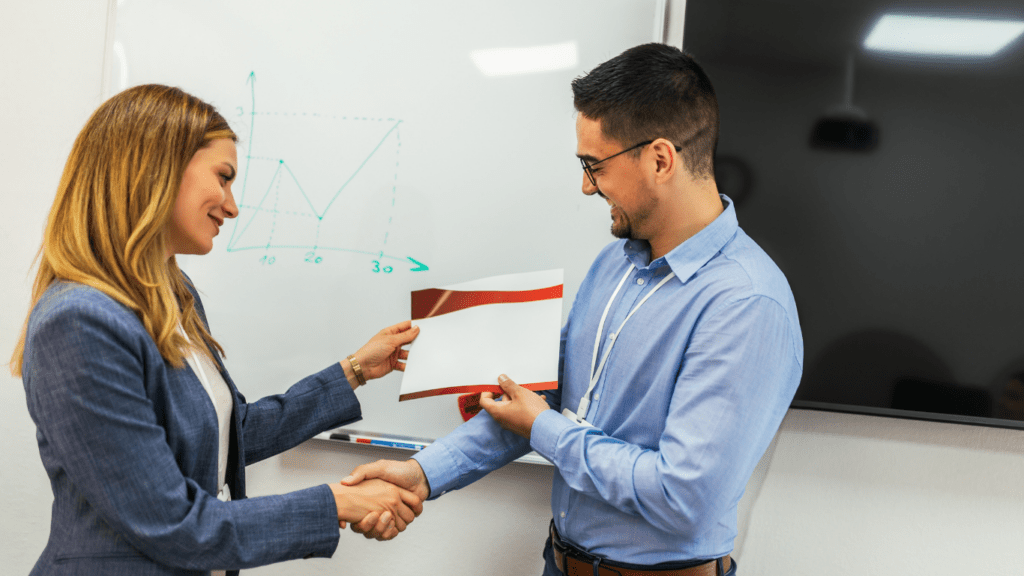 Two people shaking hands in front of a whiteboard