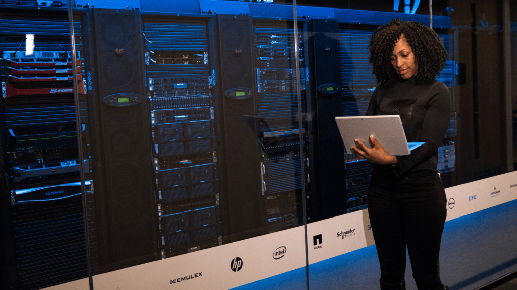 a person holding a laptop in front of a server room