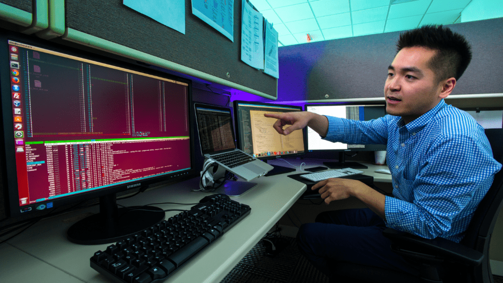 two individuals working on computers in an office